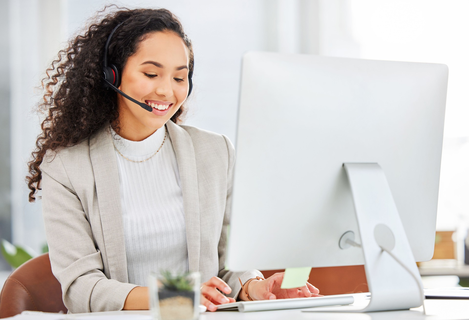 Shot of a young businesswoman wearing a headset while working on a computer in an office